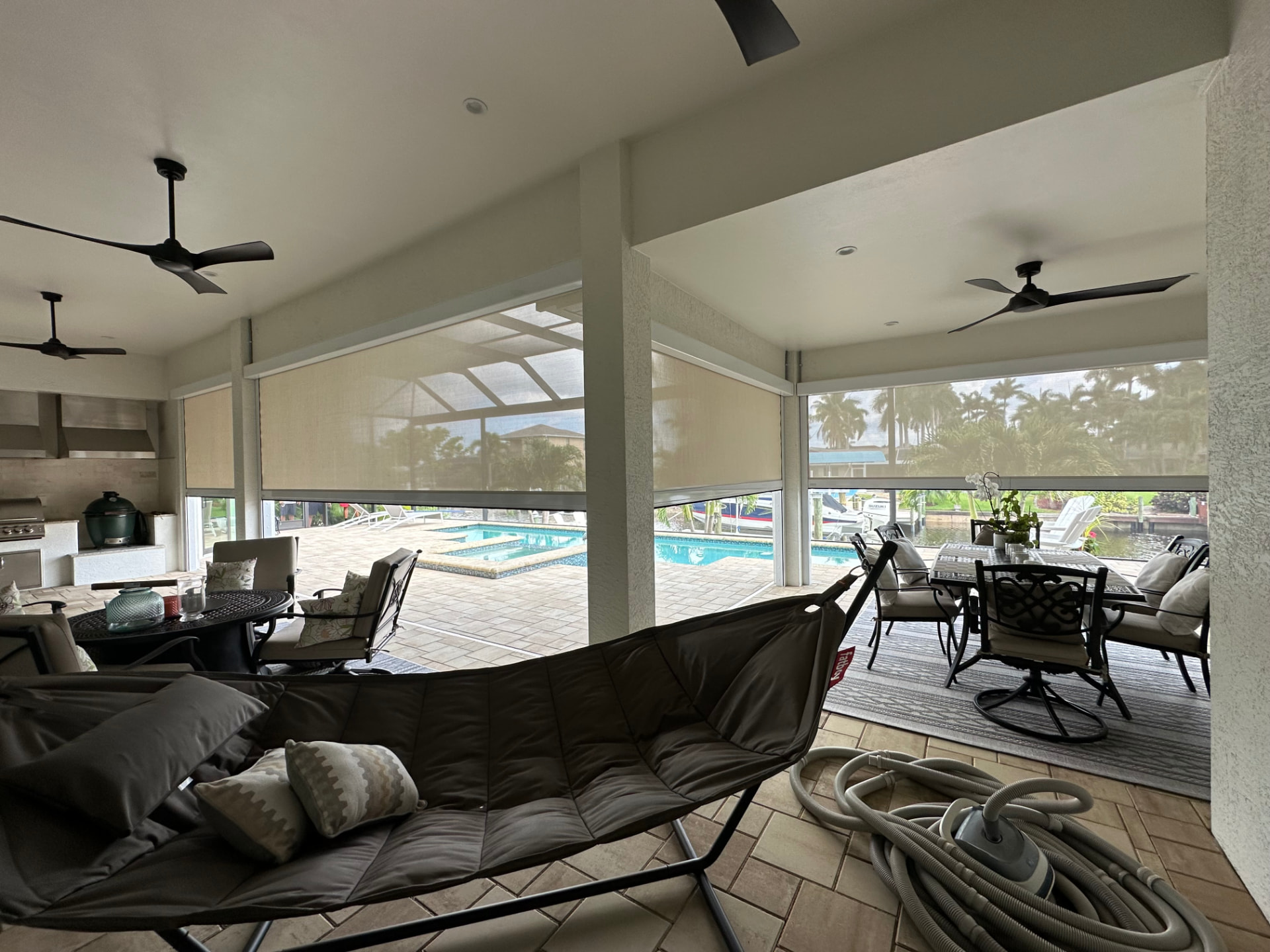 White roll-down screens across the openings of a furnished covered patio