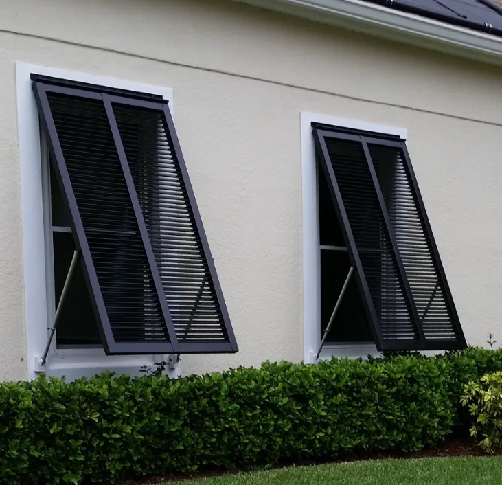 Product visualization of dark Bahama shutters angled open over two windows on a light stucco wall — a rendering, not a verified installation