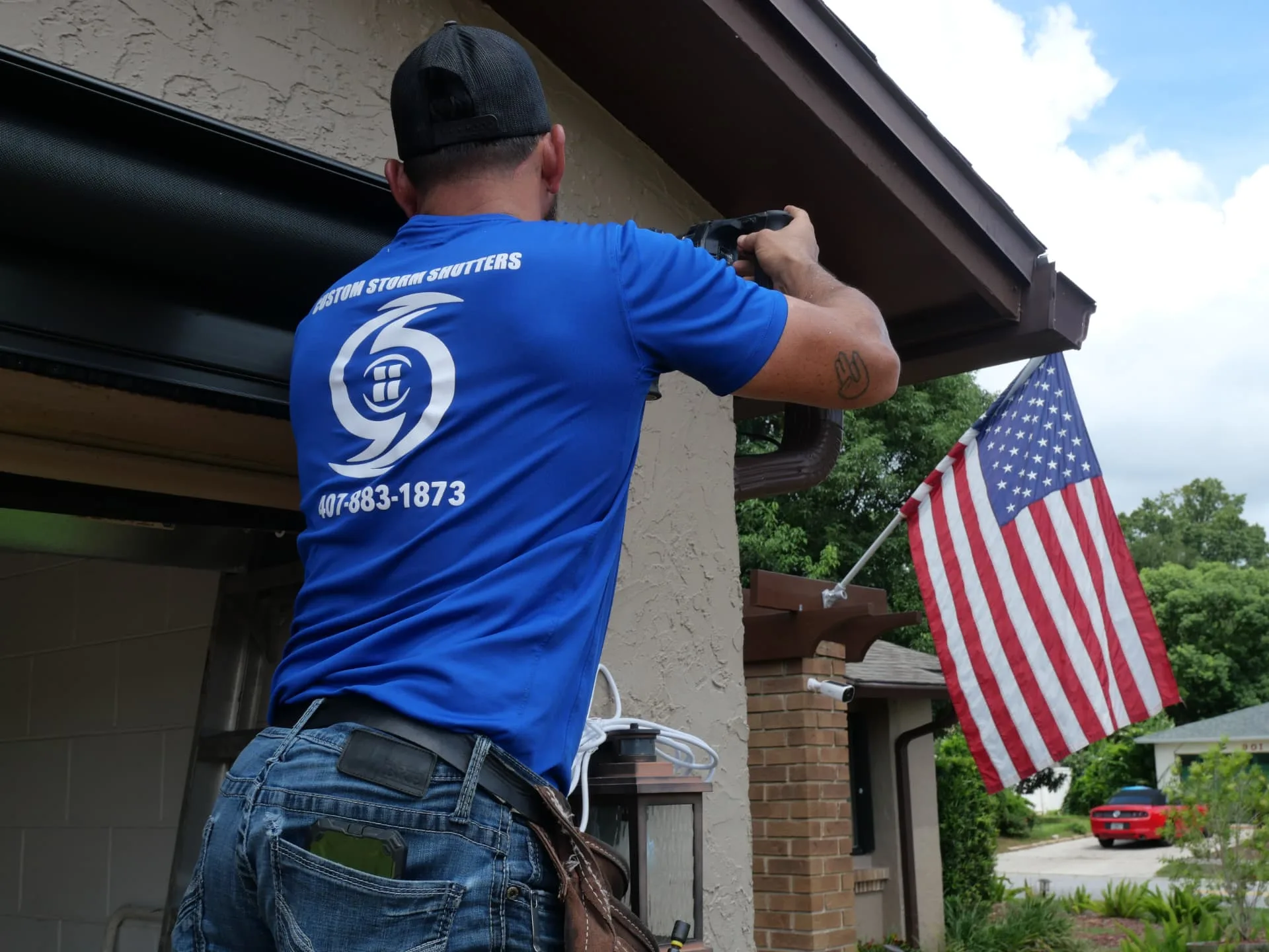 Installer fastening a bronze UltraShield screen housing above a garage opening