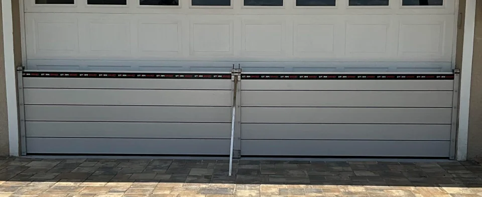 Flood barrier for a double garage: stacked aluminum Flood Smart panels with a center post and stainless support arm